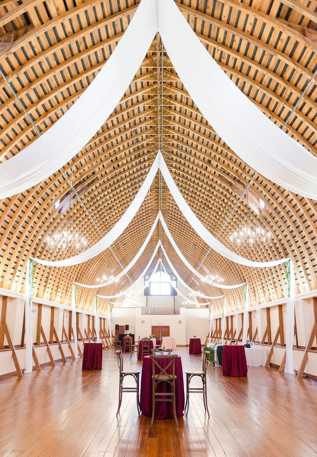 The Loft’s arched timber roof with draped fabric and chandeliers